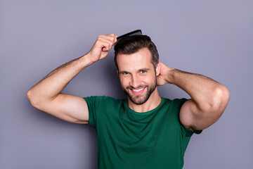 Portrait of positive guy comb haircut after spa salon procedure wash enjoy haircare therapy wear green t-shirt isolated over gray color background