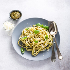 Homemade pasta, spaghetti, linguine with green pesto and basil. Italian healthy food concept with copy space, top view.
