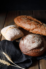 Variety of loaves of bread and buns on wooden table background
