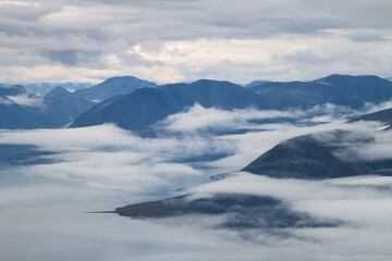 Obraz na płótnie Canvas Majestic mountain landscape. Scenic aerial view of the sea bay and mountains in the clouds. Beautiful nature of the Arctic. Location: Providence Bay, Bering Sea, Chukotka, Siberia, Far East of Russia.