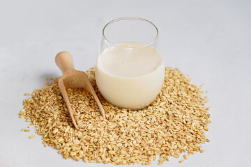 Vegan non dairy alternative oat milk in glass. Oat cereal in wooden spoo on stone table. concept of vegetarian diet eating, dieting, sport and fitness menu