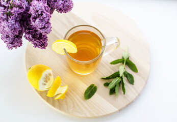 A cup of tea with lemon and lilac flowers