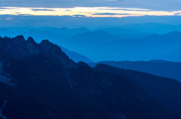Spectacular view of blue mountain ranges silhouettes and fog in valleys. Julian Alps, Triglav National Park, Slovenia. View from Mountain Slemenova, Sleme.