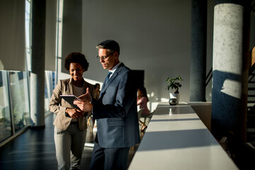 Multiethnic business people using digital tablet while standing in the office