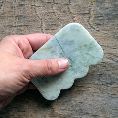 hand holding jade guasha tool