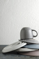 Vertical image.Concept of washing dishes.Stack of wet and clean plates, cup on the grey kitchen table against white wall