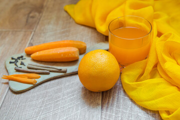 Orange and carrot juice. Carrot juice. Healthy food, healthy drink. Orange juice in a glass and next Orang, peeled carrots. healthy eating for breakfast. Wood background