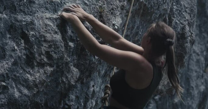 Female paralympic climber woman athlete with missing fingers on left hand struggle and fail to rock climb hold grip ascend outdoors lifestyle sport in nature