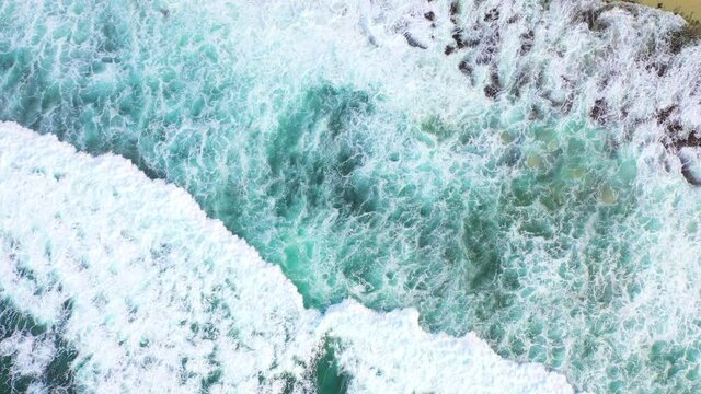 Bali - big ocean waves hitting a coral reef and a rocky beach, view from above. Aerial 4k footage.	