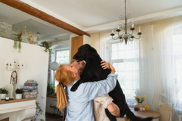 young couple at home playing with their dog. man holding dog on his shoulders. couple holding their...