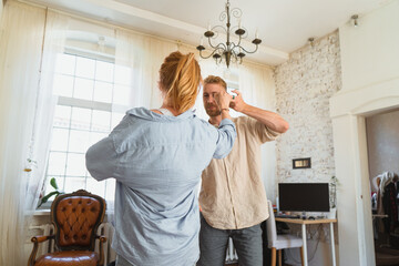 young couple, redhead man and woman are dancing in their flat, couple spending leisure time together and having fun