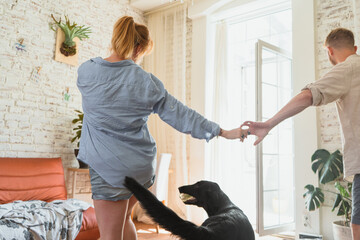 young couple, redhead man and woman are dancing in their flat, couple spending leisure time together and having fun with their dog