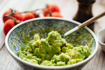 Mashed avocado in a bowl. Guacamole sauce, avocado mash. Closeup view, selective focus