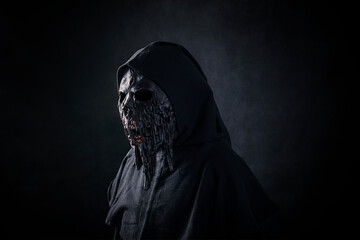 Scary figure in hooded cloak with mask