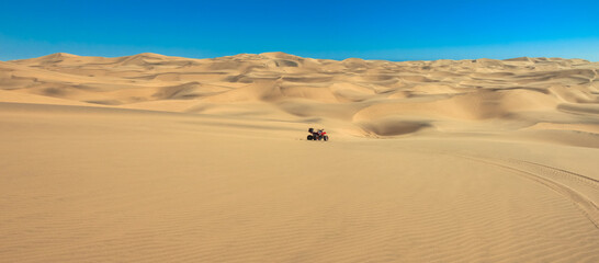 Fototapeta na wymiar Quad driving in sand desert. ATV standing in middle of nowhere in sand dunes desert with skid marks. Africa, Namibia, Namib, near Walvis Bay, Swakopmund.
