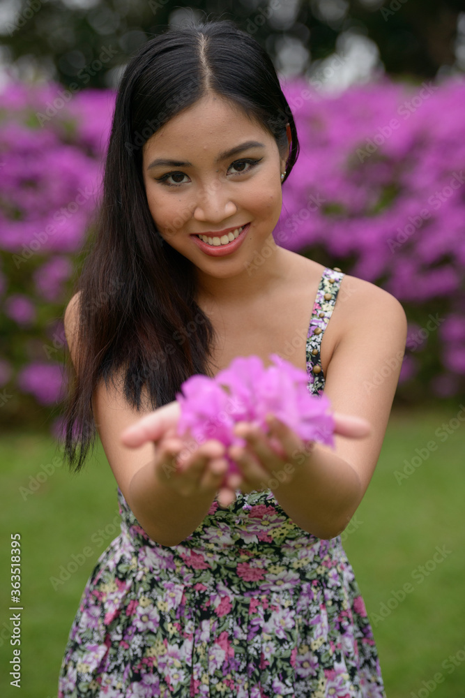 Wall mural portrait of happy young beautiful asian woman giving flowers at the park