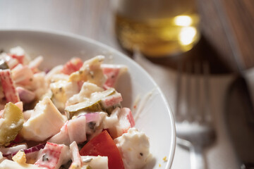 Crab stick salad in focus, Glass with beer and fork out of focus. Restaurant food concept.