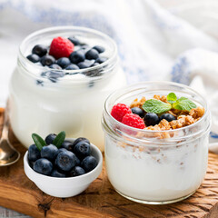 Greek yogurt with granola and berries in a jar. Healthy yogurt snack with crunchy oats granola and summer berries