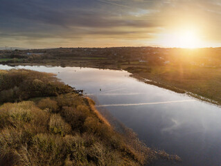 Fototapeta na wymiar River Corrib in County Galway at sunset, Dark and moody sky, Warm sun light. Nobody. Aerial view.