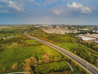 Fototapeta na wymiar Empty highway near Galway city, Blue cloudy sky, Houses and commercial property on the right. Warm sunny day, Aerial view.
