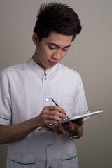 Portrait of young handsome Asian businessman using digital tablet