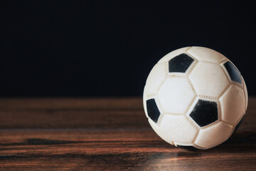 Classic foot ball on dark wood floor in a game hall. Copy space. Dark background.