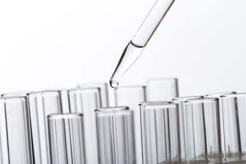 pipette with a drop and scientific laboratory test tubes in a research laboratory.