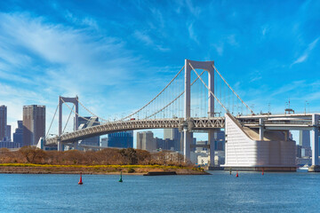 Bird Island of Odaiba Bay in front of the double-layered suspension Rainbow Bridge in the port of Tokyo with cirrus clouds in the sky.