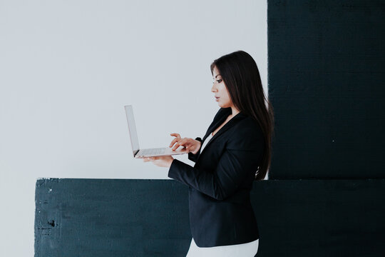 Beautiful brunette woman in white and black business business clothes in the office with a laptop
