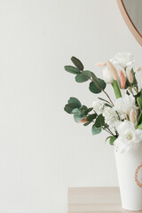 Artificial flowers in the bathroom interior. Decorative flowers in the bathroom. Artificial flowers in a vase. White bathroom interior. Decorative flowers. 
