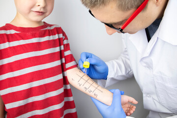 An allergist doctor makes a skin test for allergies. The boy is being examined in the laboratory,...