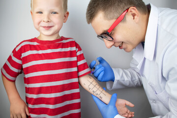 An allergist doctor makes a skin test for allergies. The boy is being examined in the laboratory,...
