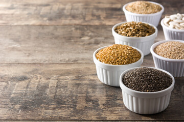 Assortment of different seeds in bowl on wooden table. Pumpkin, linen, chia, sunflower and sesame seeds. 