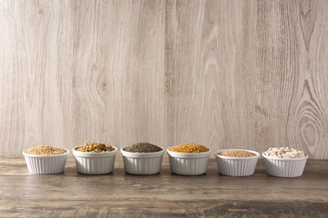 Assortment of different seeds in bowl on wooden table. Pumpkin, linen, chia, sunflower and sesame seeds. 