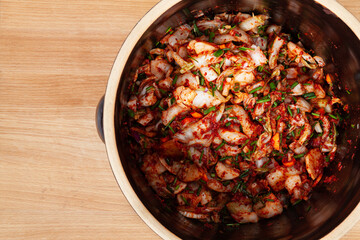 Cut vegetables mixed with gochugaru chili powder marinate in clay pot. Mixture ready for fermentation to make kimchi traditional Asian food.