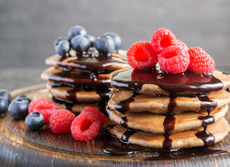 Chocolate pancakes with raspberry on a dark background.