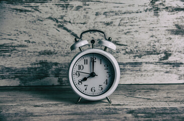 Vintage alarm clock with old white bells, with white painted aged wooden background. Concept of a retro clock
