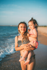 Mother with her daughter in her arms against the background of the sea of Azov in Crimea