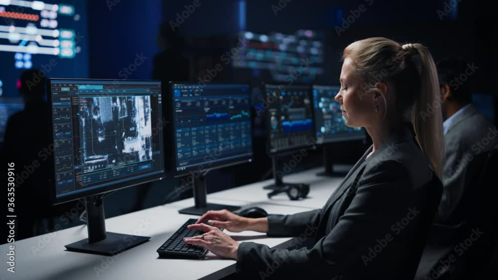 Poster female cyber security agent works on personal computer showing footage of drone surveillance trackin
