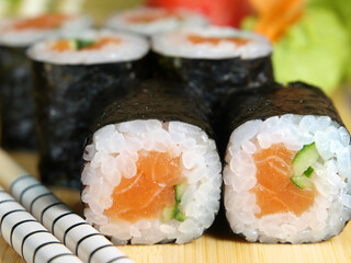 Japanese maki roll with salmon and cucumber on a wooden tray close-up