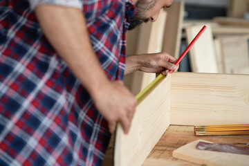 Fototapeta na wymiar Back view of carpenter measuring wooden plank