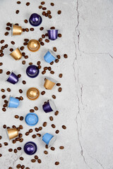 Caffeine, hot drinks and objects concept. Close up colorful capsules or pods for coffee mashine with some roasted grains on gray concrete background. Top view with space for text. Selective Focus.