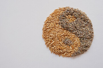 Oats grain and dried lavender flowers, forming Yin Yang on white background. Natural herbal medicines are used to treat anxiety and sleep disorders. Nervines. Top view.
