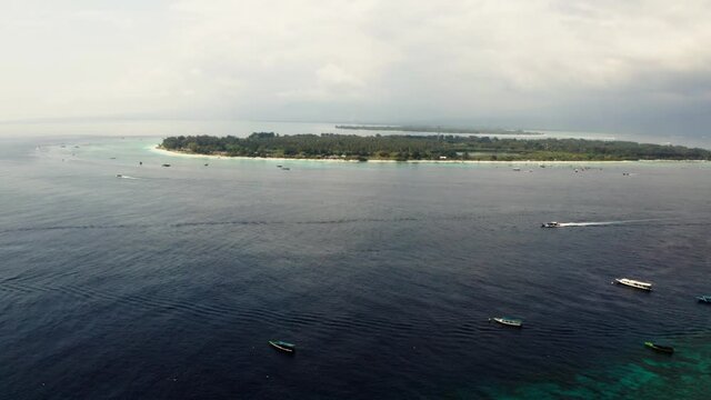 Summer time in the Gili Travangan Island with cruise boats. Aerial drone shot of the island nearby.