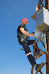 Electrician with  safety belt on a pole repairs Circuit breakers