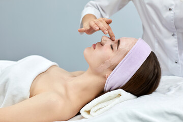 Fototapeta na wymiar beautician applies the mask to female face in the spa salon. spa treatments