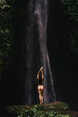 Young and beautiful girl taking bath in a waterfall