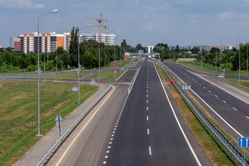 Highway against the background of high-rise buildings and a construction crane at the entrance to the city.