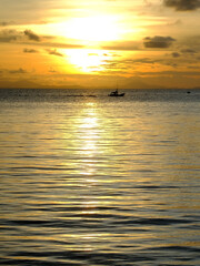 Golden sky during the sunset and Silhouette of fishing boat on the sea in Thailand.