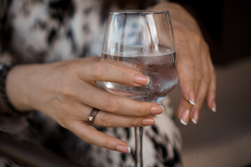 Female hand holding a wine glass with water